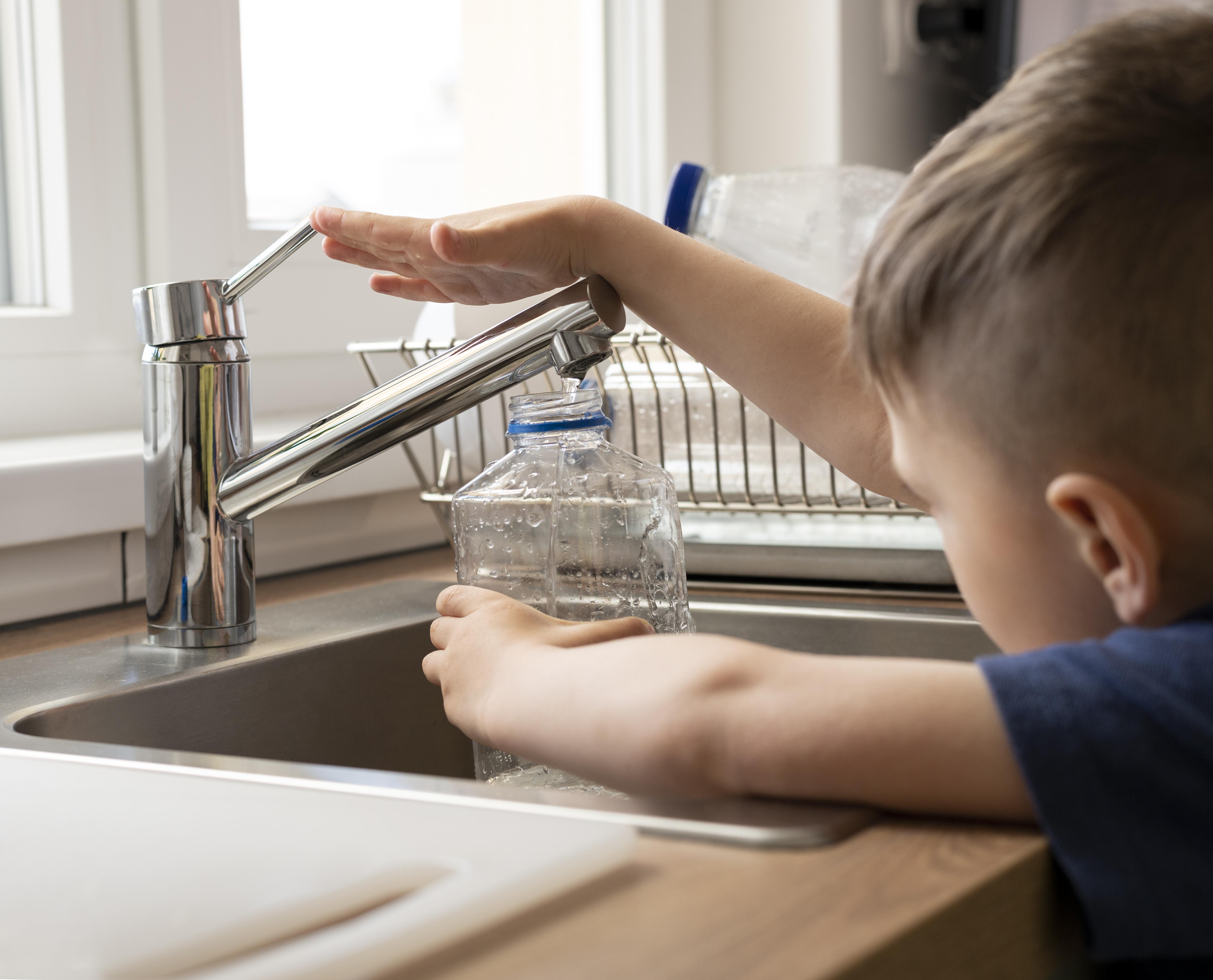 close-up-kid-filling-bottle-with-water